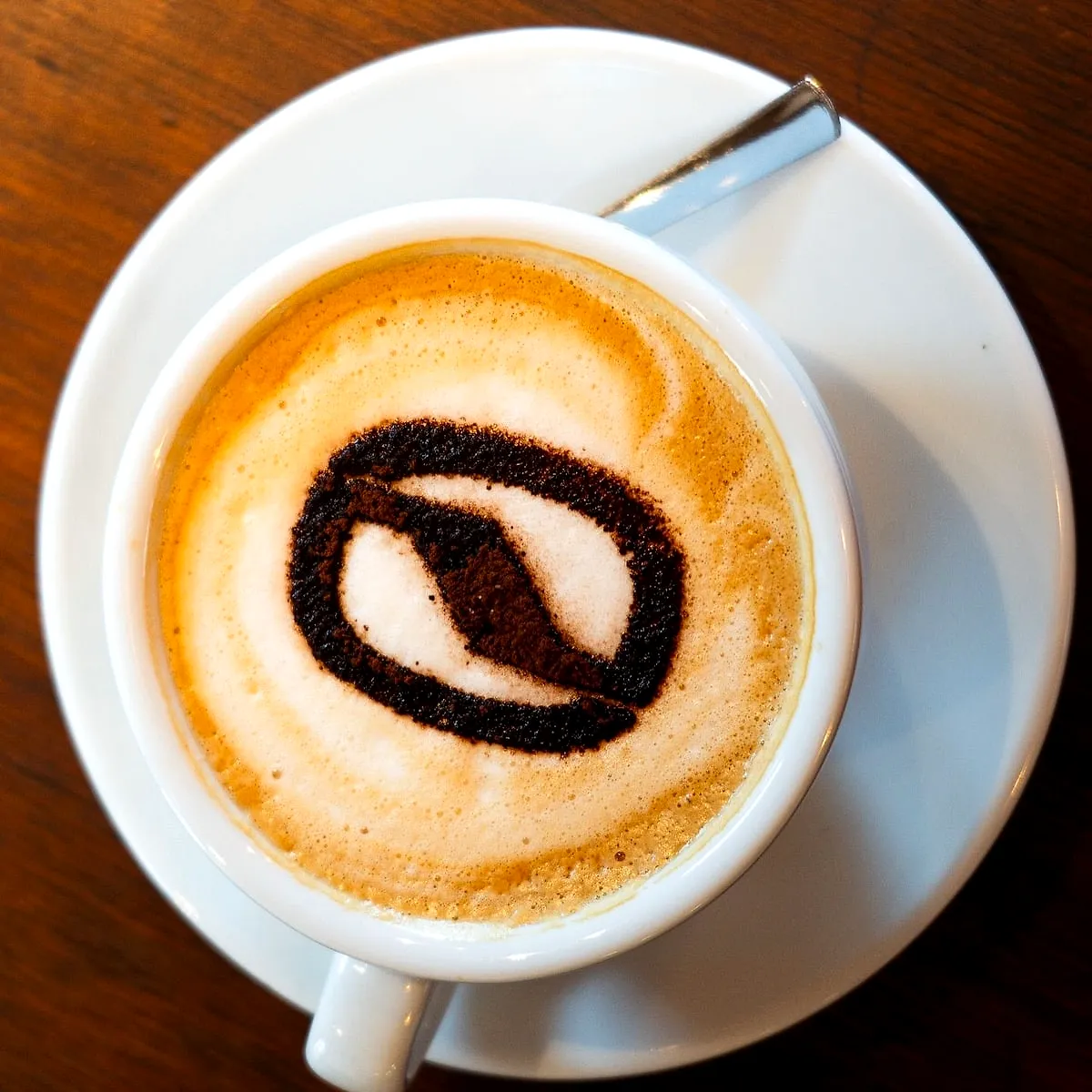 Un cappuccino avec un grain de café dessiné dans la mousse