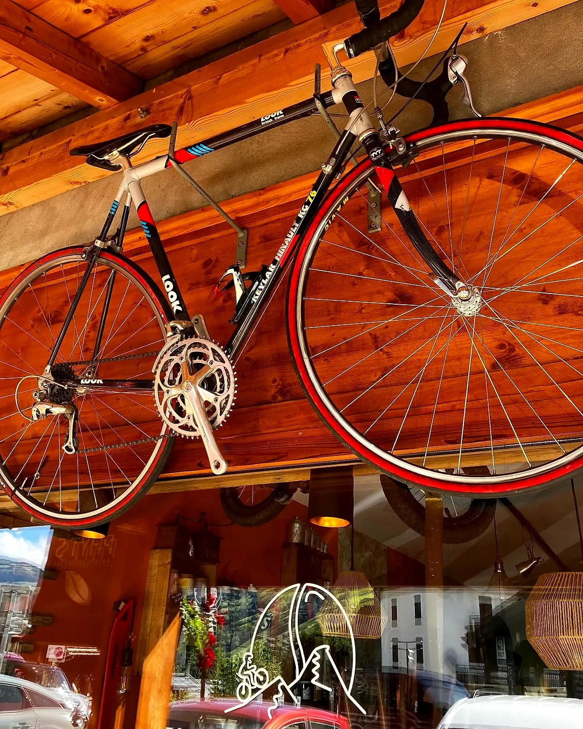 Un vélo de course rouge accroché au plafond en bois